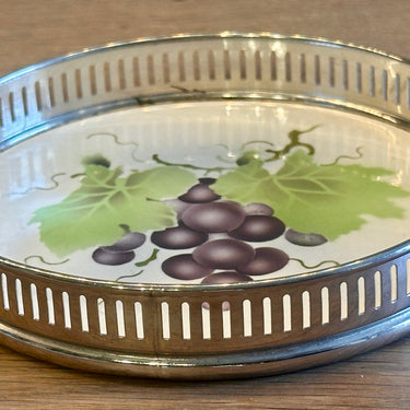 Onderzetter - voor glas of fles - ongemerkt (alleen nr. 5076 onderzijde) - opstaande rand in chroom - aardewerk plateau met décor van druiven in paars en groen