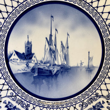 Wandbord - groot - ongemerkt - met ophangoog - in het midden een blauw spuitdecor van oude schepen, een kerkje en molens