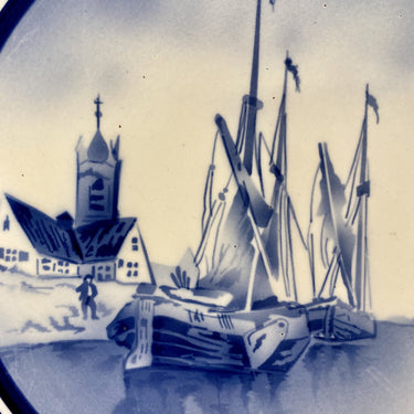 Wandbord - groot - ongemerkt - met ophangoog - in het midden een blauw spuitdecor van oude schepen, een kerkje en molens